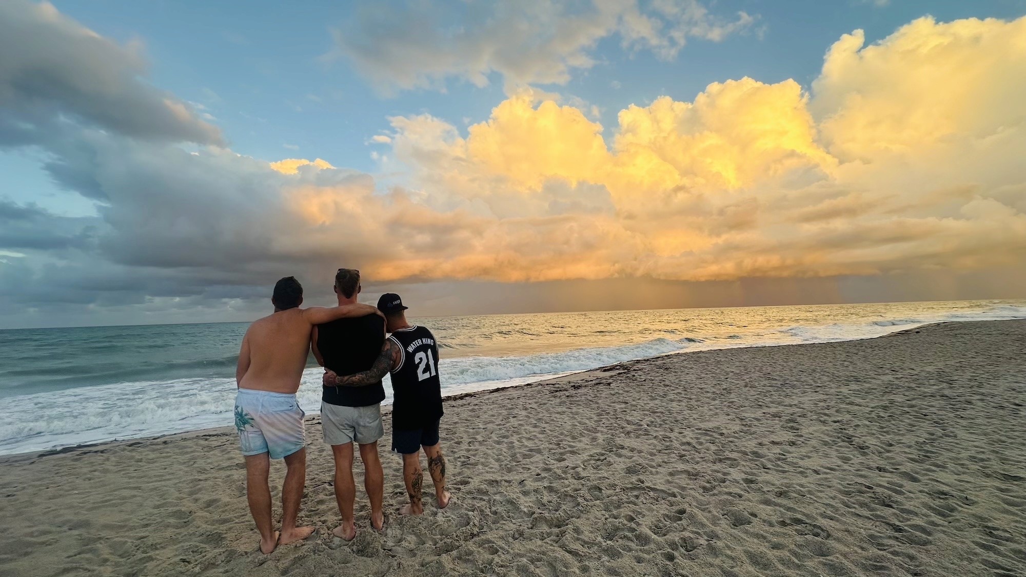 Men standing together at the shoreline at sunrise